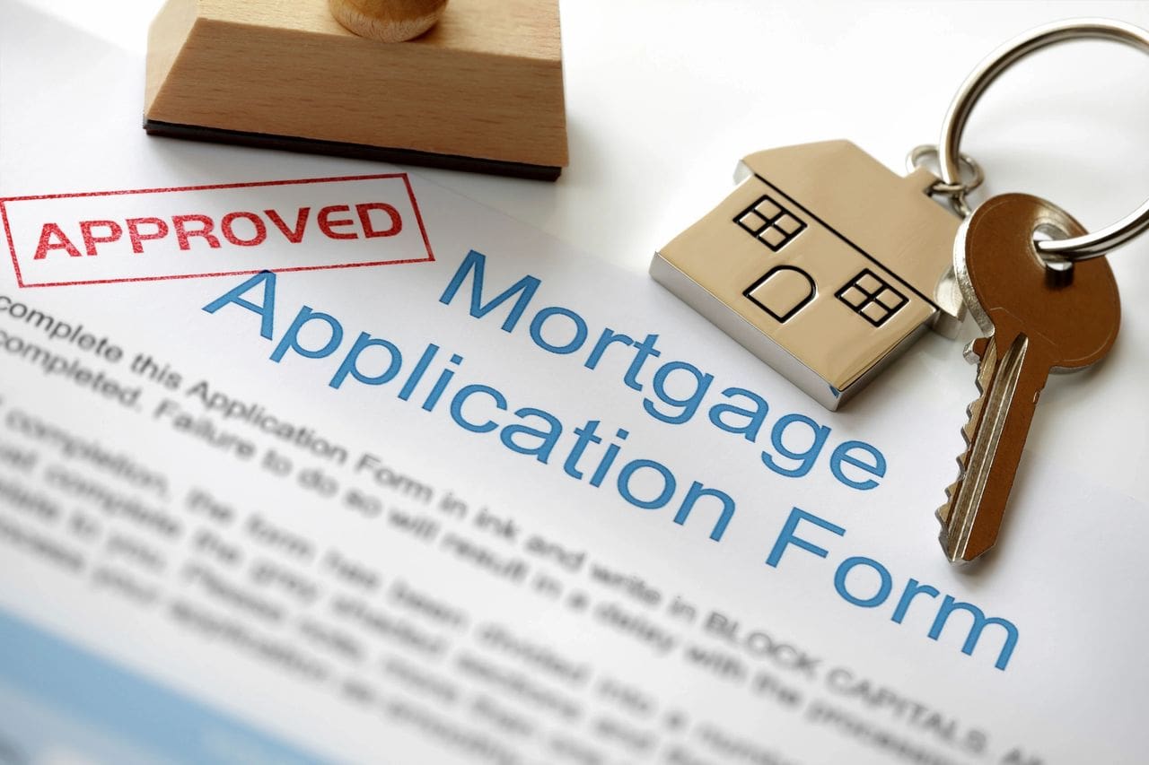 Mortgage application form with approved stamp and wooden house model.